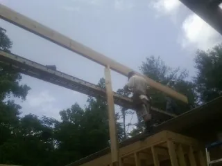 Carpenter setting a ridge beam over a new addition frame — Ice Dam Removal by Roofing Brothers in Nancy