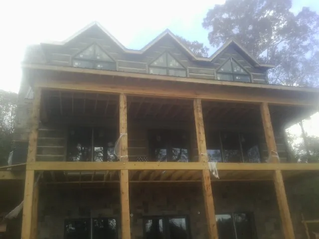 Dormers and porch framing on a large log home under construction — Roof Coating work by our crew in Nancy