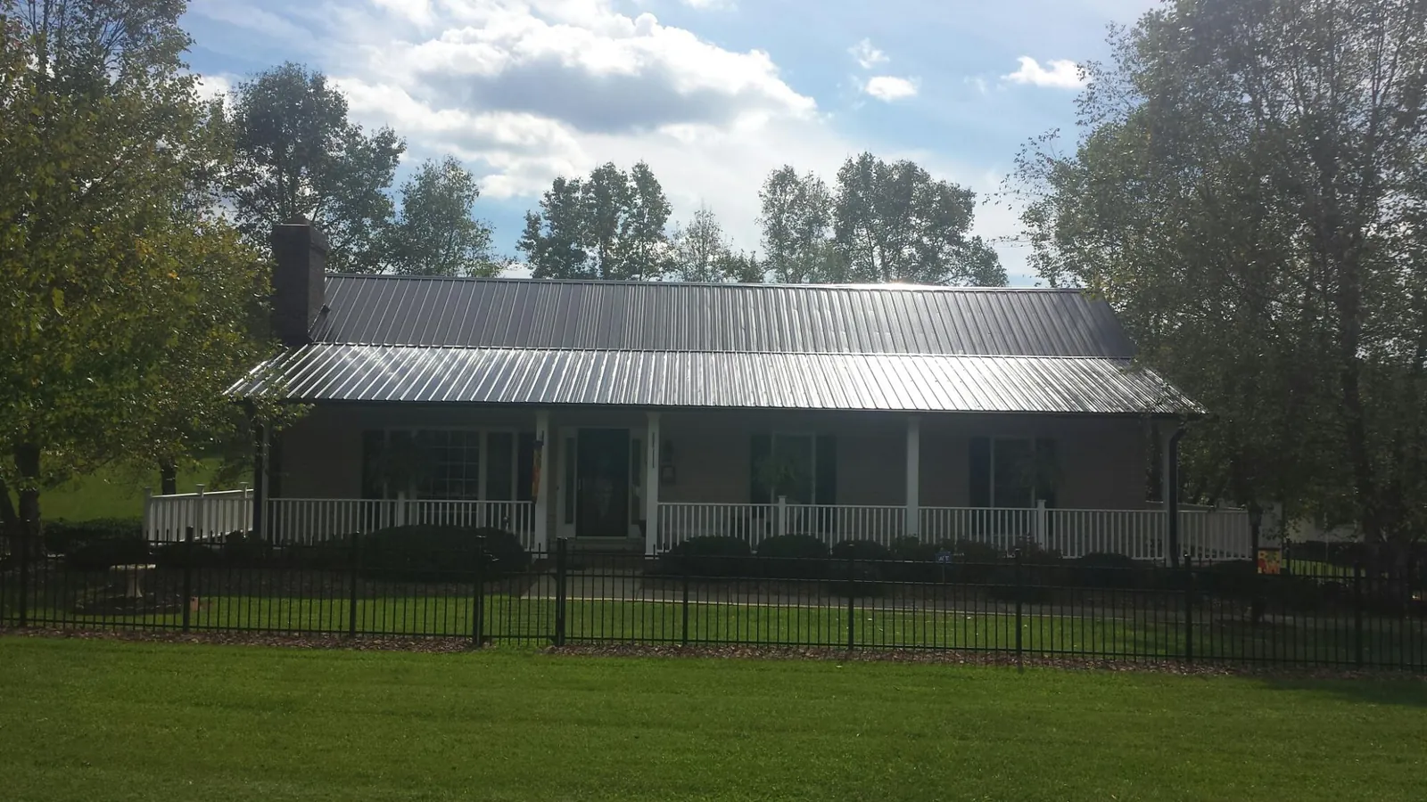 Gray metal roof on a brick ranch with a full width front porch — Gutter Guard Installation work by our crew in Nancy