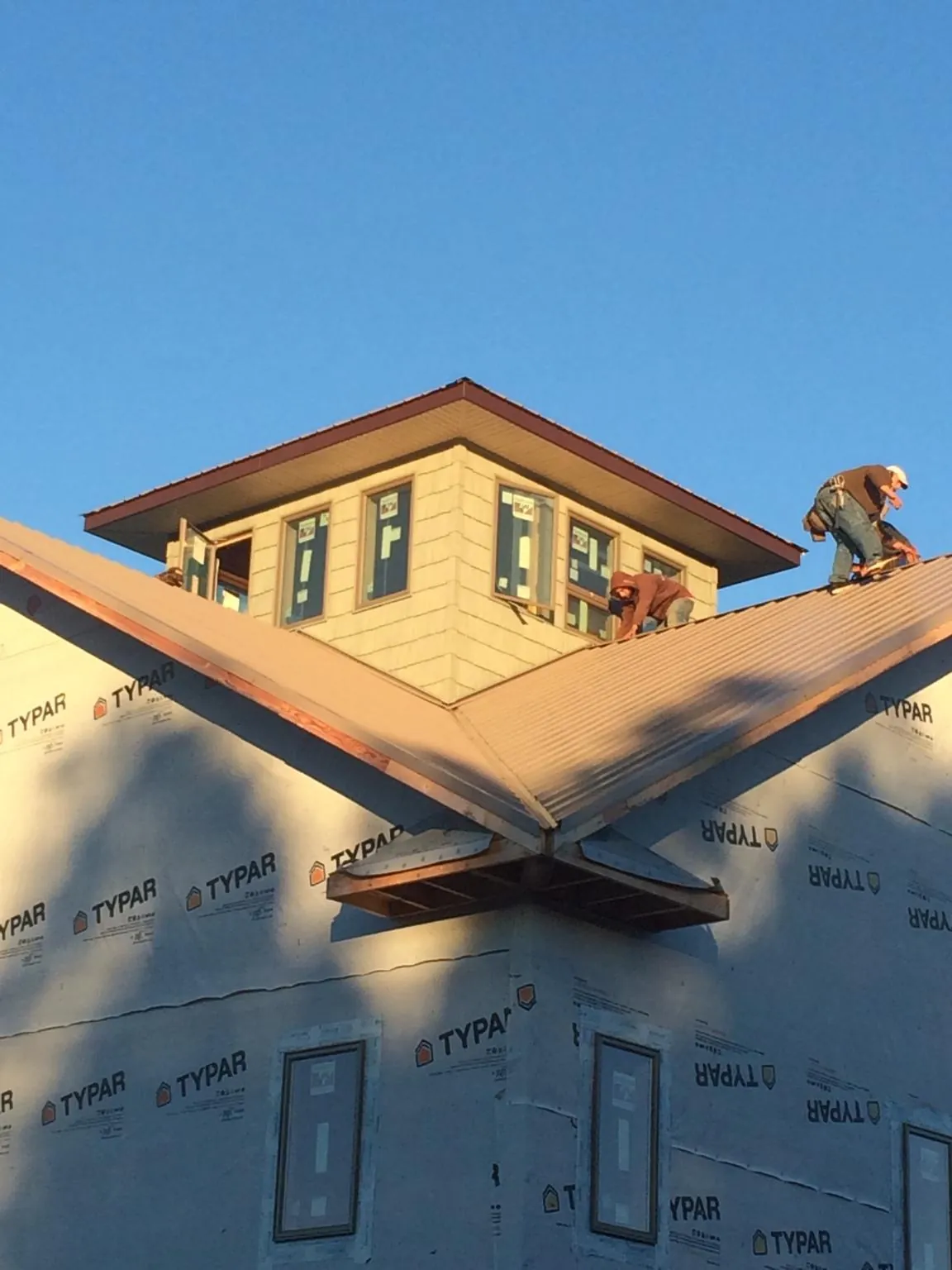 Roofers working around a rooftop cupola on a new metal roof at sunset — Roof Waterproofing in Nancy by Roofing Brothers